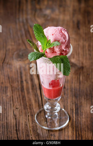 Bicchiere di dessert di fragole con sorbetto e menta, servita in legno sfondo a trama. Foto Stock