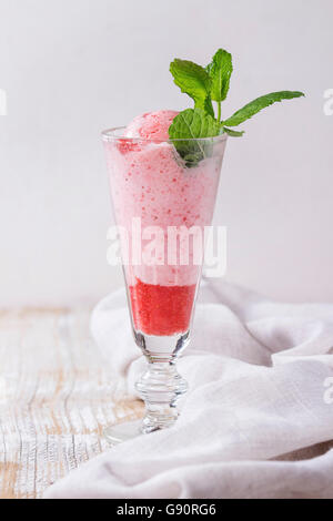 Bicchiere di dessert di fragole con sorbetto e menta, serviti nel corso di legno bianco sullo sfondo a trama con tessili rag. Foto Stock