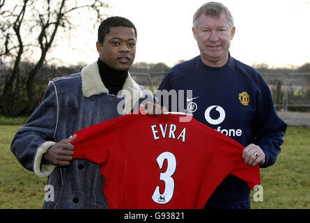 Manchester United nuovo firma Patrice Evra con il manager Sir Alex Ferguson (R) tiene la sua maglia al campo di allenamento di Carrington, giovedì 12 gennaio 2006. PREMERE ASSOCIAZIONE foto. Il credito fotografico dovrebbe essere: Phil Noble/PA. Foto Stock