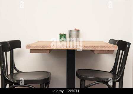 Tavolo in legno con due sedie e un muro bianco sullo sfondo Foto Stock