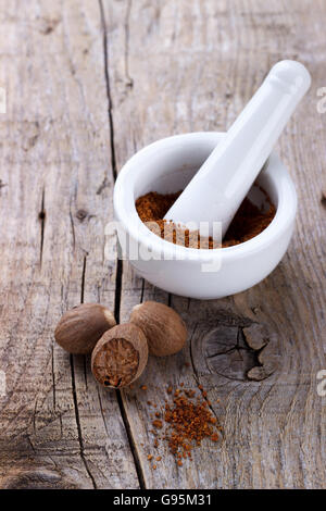 Noce moscata grattugiata spice in un mortaio in legno rustico sfondo, closeup.Il fuoco selettivo Foto Stock