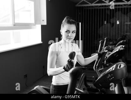 Bellissima fanciulla facendo formazione sulla macchina ellittica in palestra. Concetto di salute e fitness. Foto Stock