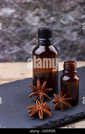 Anice olio essenziale in piccoli flaconi su pietra nera, messa a fuoco selezionata Foto Stock