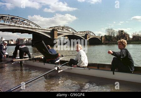 Un vogatore getta i suoi wellies fuori dalla barca prima dell'inizio della corsa del capo delle donne del fiume, da Mortlake a Putney. Foto Stock