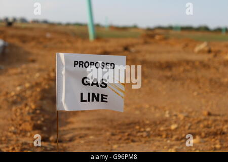 Una linea di gas in una nuova costruzione di abitazioni Zona. Un flag nella parte anteriore di sporcizia, erba, alberi, Sky, rocce e tubo - Nuovo quartiere. Foto Stock