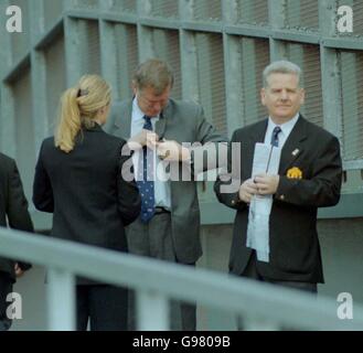 Sir Alex Ferguson, direttore del Manchester United (al centro), regola il suo 2006 Badge a lappone per l'arrivo del team di ispezione FIFA A Old Trafford Foto Stock