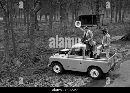 Il marchese di Bath, sostenuto da un guardiano armato, alza il cappello ad uno dei leoni che sarà un'attrazione di stella nella sua 'riserva di gioco' che si apre alla sua casa ancestrale Wiltshire, Longleat, il 5 aprile 1966. Il marchese ha tenuto una giornata di rassegna stampa presso la riserva di 100 acri in cui i Lions gireranno. Il parco dei leoni è delimitato da una recinzione di 14 piedi. Foto Stock