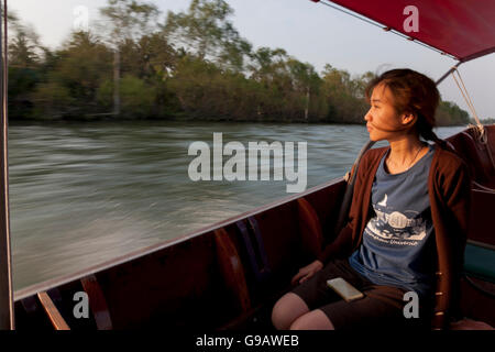 Un tailandese donna seduta in una longtail boat sul fiume Maeklong in Thailandia. Foto Stock