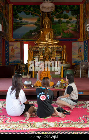 Un gruppo di Thais parlando di un monaco dopo la conduzione di preghiere nel tempio principale hall di Wat Phummarin in Maeklong in Thailandia. Foto Stock