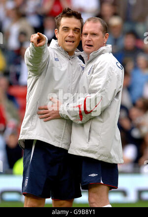 Il capitano della squadra inglese Robbie Williams (a sinistra) condivide una battuta con Paul Gascoigne prima del calcio d'inizio, durante la partita di calcio benefica dell'UNICEF Soccer Aid, a Old Trafford, Manchester. Foto Stock