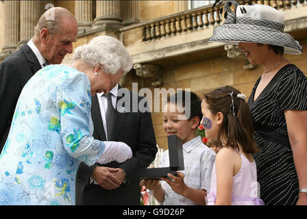 La Gran Bretagna è la Regina Elisabetta II riceve un ottantesimo compleanno medaglia da 8 anno vecchio Takeo Boradhurst, durante il giardino dei bambini festa a Buckingham Palace di Londra,la scuola da ragazzo Bromley, Essex ha vinto un concorso della BBC, per progettare la medaglia.passeggiate attraverso l'area pic-nic. Foto Stock