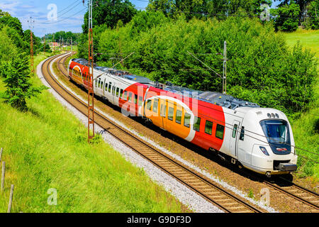 Norsholm, Svezia - 20 Giugno 2016: colorato treno passa su una doppia stazione cingolato sulla campagna. Il treno è chiamato Ostgota Foto Stock