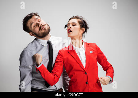 L'arrabbiato business l uomo e la donna in conflitto tra loro su uno sfondo grigio Foto Stock