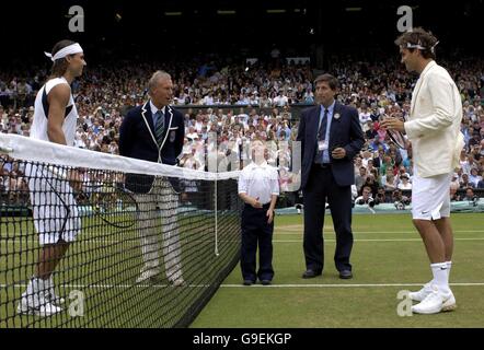 William Caines, di sette anni, di Beckenham, Kent, rappresenta Cancer Research UK mentre esegue il lancio della moneta in vista della partita finale dei singoli uomini tra Roger Federer (a destra) e Rafael Nadal (a sinistra) della Svizzera durante i Campionati di tennis All England Lawn a Wimbledon. Foto Stock