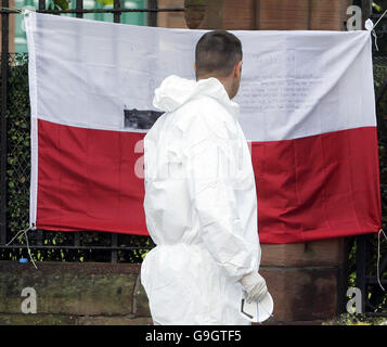 Un ufficiale forense legge una nota su una bandiera polacca fuori della chiesa di San Patrizio a Glasgow, dopo che un uomo voluto per l'omicidio della studentessa polacca Angelika Kluk è stato tenuto dalla polizia come hanno confermato un corpo trovato nella chiesa è stato suo. Foto Stock