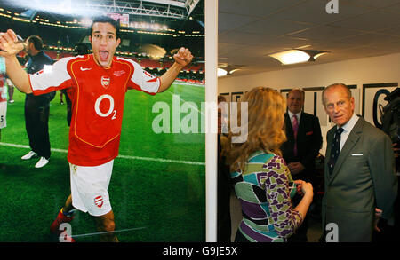 Il principe Filippo (R) della Gran Bretagna incontra i dipendenti del Learning Center presso la squadra di calcio dell'Arsenal accanto a un poster del giocatore Robin van Persie (L) mentre apre ufficialmente lo Emirates Stadium a Londra, il 26 ottobre 2006. Prince Philip ha partecipato all'evento da solo giovedì dopo che la regina Elisabetta II ha annullato la visita al nuovo stadio della prima squadra di calcio inglese Arsenal a causa di un muscolo teso nella sua schiena, ha detto il suo ufficio. Il monarca di 80 anni -- sul trono dal 1952 -- aveva dovuto aprire ufficialmente il nuovo Emirates Stadium di Gunners nel nord di Londra accompagnato dal marito di 85 anni Foto Stock