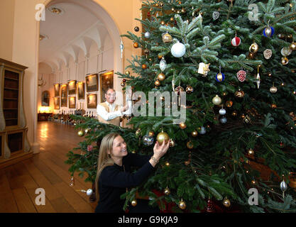 L'Hon Simon Howard e sua moglie Rebecca finiscono di decorare l'albero di Natale nella Great Hall of Castle Howard, York. Foto Stock