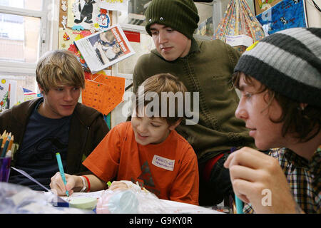 I membri di McFly (da sinistra a destra) Dougie Poynter, Tom Fletcher e Danny Jones aiutano Fergus Hunt, 11 anni da Chelmsford in Essex, a progettare una cartolina di Natale al Great Ormond Street Children's Hospital nel centro di Londra. Foto Stock