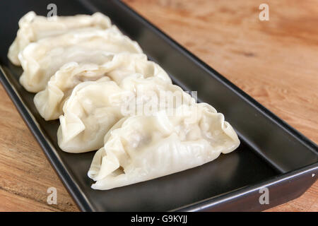 Gnocco wonton (giapponesi Gyoza) sul piatto nero Foto Stock