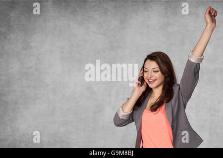 Felice imprenditrice, mano sollevata fino in un gesto di successo Foto Stock