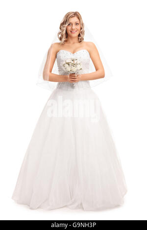 A piena lunghezza Ritratto di una giovane sposa bionda tenendo un fiore di nozze e guardando la telecamera isolata su sfondo bianco Foto Stock