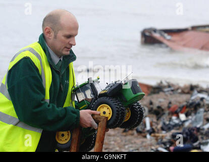 Un beachcomber raccoglie un trattore giocattolo che è stato lavato sulla spiaggia di Branscombe nel Devon. Foto Stock