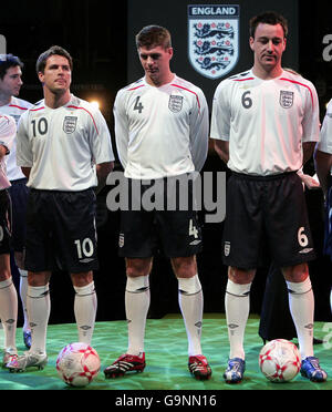 Il capitano inglese John Terry (a destra), Steven Gerrard e Michael Owen (a sinistra) modellano la nuova divisa nazionale al Royal Exchange Theatre di Manchester. Foto Stock