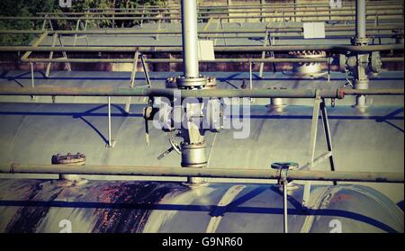 Tubi di grandi dimensioni e di una valvola di sicurezza oltre il gigantesco serbatoio di stoccaggio del gas propano in stabilimento industriale Foto Stock