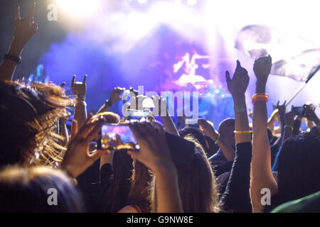 Le persone scattano fotografie con touch smart phone durante un intrattenimento musicale di concerto in pubblico le mani in aria Foto Stock