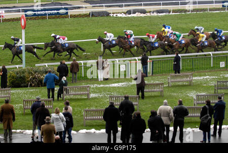 I corridori e i piloti della Range Rover Novices' Hurdle Race passano il posto vincente e la tribuna principale sul primo circuito della loro gara di 2 miglia 5 furlong all'ippodromo di Kempton Park. Foto Stock