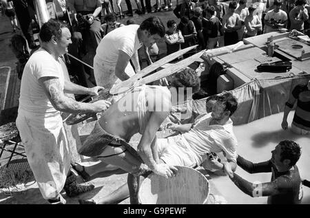 La 'bellezza' non identificata in un reggiseno (primo piano) a bordo della HMS Hermes assiste alla Corte del re Nettuno nella cerimonia 'attraversare la linea' vittime di nemici che non aveva mai attraversato l'Equatore in mare. Centinaia furono condannati e ricevettero certificati per commemorare la giornata, mentre il portaerei gigante si spostò verso le Falklands occupate. Foto Stock