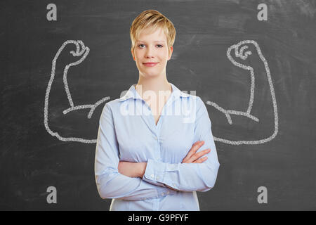 Strong business donna con chalk muscoli di fronte a una lavagna Foto Stock