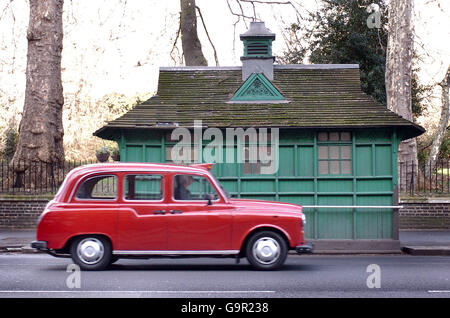 Un taxi di Londra passa davanti al rifugio di un tassista a Knightsbridge di Londra. Foto Stock