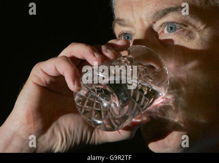 Il primo ministro britannico Tony Blair si ferma per un drink mentre si rivolge ai giornalisti durante la sua conferenza stampa mensile a No10 Downing Street, Londra. Foto Stock