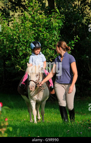 Donna figlia leader su pony Shetland / leadline, a piedi Foto Stock