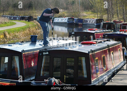 L'uomo pulisce la chiatta. Un uomo pulisce le barche del canale sul Forth e Clyde Canal vicino alla ruota Falkirk. Foto Stock