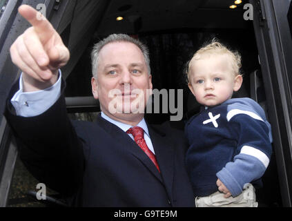 Il primo ministro scozzese Jack McConnell trasporta un bambino giovane durante una passeggiata elettorale al complesso di Loch Lomond Shores a Balloch, Scozia. Foto Stock