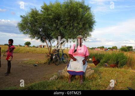 Una donna anziana siede presso una pompa dell'acqua nella cittadina di Matsakeng, vicino a Mafikeng nella provincia del Nord Ovest, in Sudafrica. C'è solo una pompa per un villaggio di 1000. Foto Stock