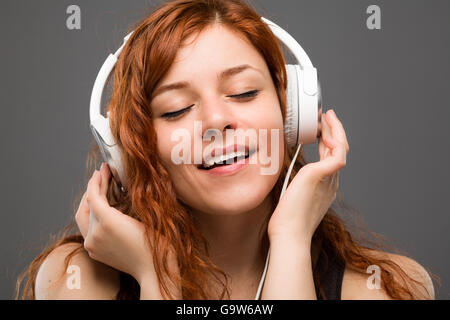 Redhead donna l'ascolto di musica con le cuffie Foto Stock