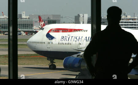 Un passeggero guarda da una finestra al Terminal 4 dell'Aeroporto di Heathrow come un Boeing 747 della British Airways taxi verso la pista. Foto Stock