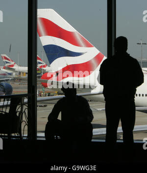 I passeggeri guardano fuori da una finestra al Terminal 4 dell'Aeroporto di Heathrow come taxi della British Airways Boeing 747 verso la pista. Foto Stock