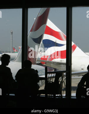I passeggeri guardano fuori da una finestra al Terminal 4 dell'Aeroporto di Heathrow mentre un aereo della British Airways taxi verso la pista. Foto Stock