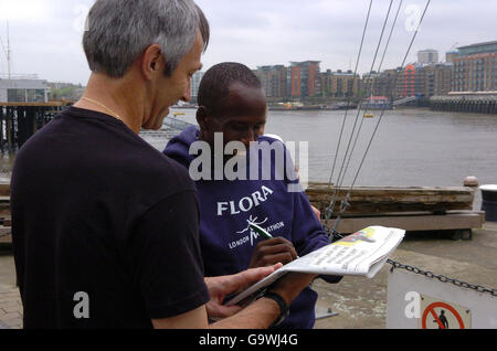 Vincitore della categoria London Marathon Elite Men, Martin LEL firma una fotografia di se stesso sul retro di un giornale per un fan di Tower Hill, nel centro di Londra. Foto Stock