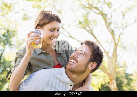 L uomo dando sovrapponibile alla donna pur avendo un bicchiere di birra Foto Stock