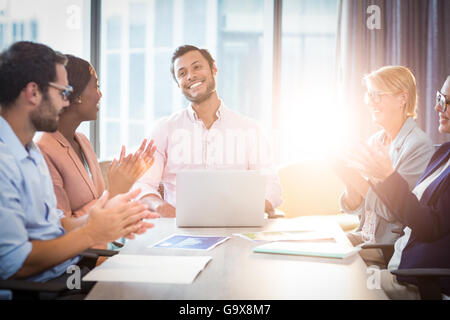 I colleghi ad applaudire un collega dopo la presentazione Foto Stock