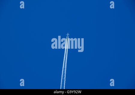 Piano lasciando contrail in un cielo blu Foto Stock