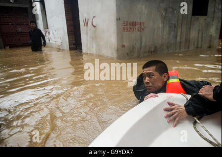 Wuhan, la Cina della provincia di Hubei. 2 Luglio, 2016. Soccorritore Liu Feng tira il motoscafo nel diluvio di approccio intrappolato paesani durante una evacuazione Xinzhou nel distretto di Wuhan, Cina centrale della provincia di Hubei, 2 luglio 2016. Alle piogge che hanno causato una violazione diga sul fiume Jushui Xinzhou nel distretto di Wuhan venerdì. Più di 700 soccorritori sono stati inviati lì per evacuare gli abitanti di un villaggio a filamento. Credito: Xiao Yijiu/Xinhua/Alamy Live News Foto Stock