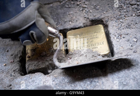 Artista tedesco Gunter Demnig luoghi 'Stolpersteine' (pietre di inciampo) in memoria di Amalie e Giuseppe Schuster, assassinati dai nazisti, sulla proprietà privata in Franz-Joseph-Strasse a Monaco di Baviera, Germania, 04 luglio 2016. Il memoriale di ottone pietre permanenti sono i promemoria degli ex residenti ebrei che furono perseguitati dai nazisti, deportati assassinati o guidati al suicidio. La città di Monaco di Baviera ha deciso ufficialmente contro la posa di scogli in luoghi pubblici con la motivazione che i nomi delle vittime del nazismo non dovrebbe essere calpestato. Foto: Sven Hoppe/dpa Foto Stock