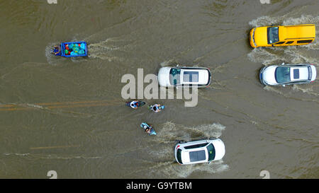 Yangzhou, cinese della provincia di Jiangsu. 5 Luglio, 2016. Di persone e di veicoli che si muovono su una strada saturo di acqua in Yangzhou, est cinese della provincia di Jiangsu, 5 luglio 2016. Un acquazzone ha colpito Yangzhou martedì. Credito: Wang Qingchao/Xinhua/Alamy Live News Foto Stock