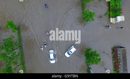 Yangzhou, cinese della provincia di Jiangsu. 5 Luglio, 2016. Di persone e di veicoli che si muovono su una strada saturo di acqua in Yangzhou, est cinese della provincia di Jiangsu, 5 luglio 2016. Un acquazzone ha colpito Yangzhou martedì. Credito: Wang Qingchao/Xinhua/Alamy Live News Foto Stock